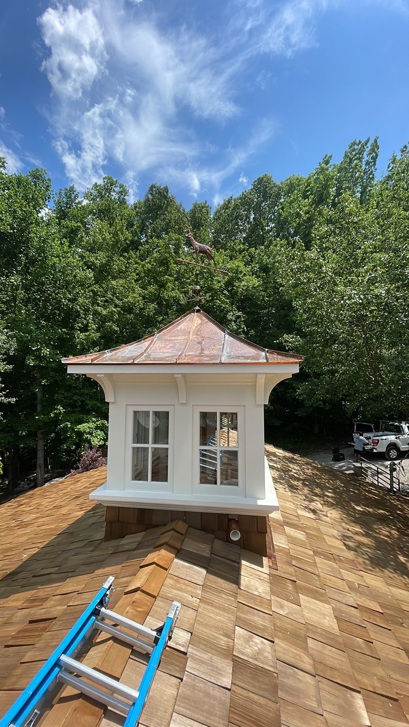 Copper cupola with a deer weathervane atop a cedar shake roof