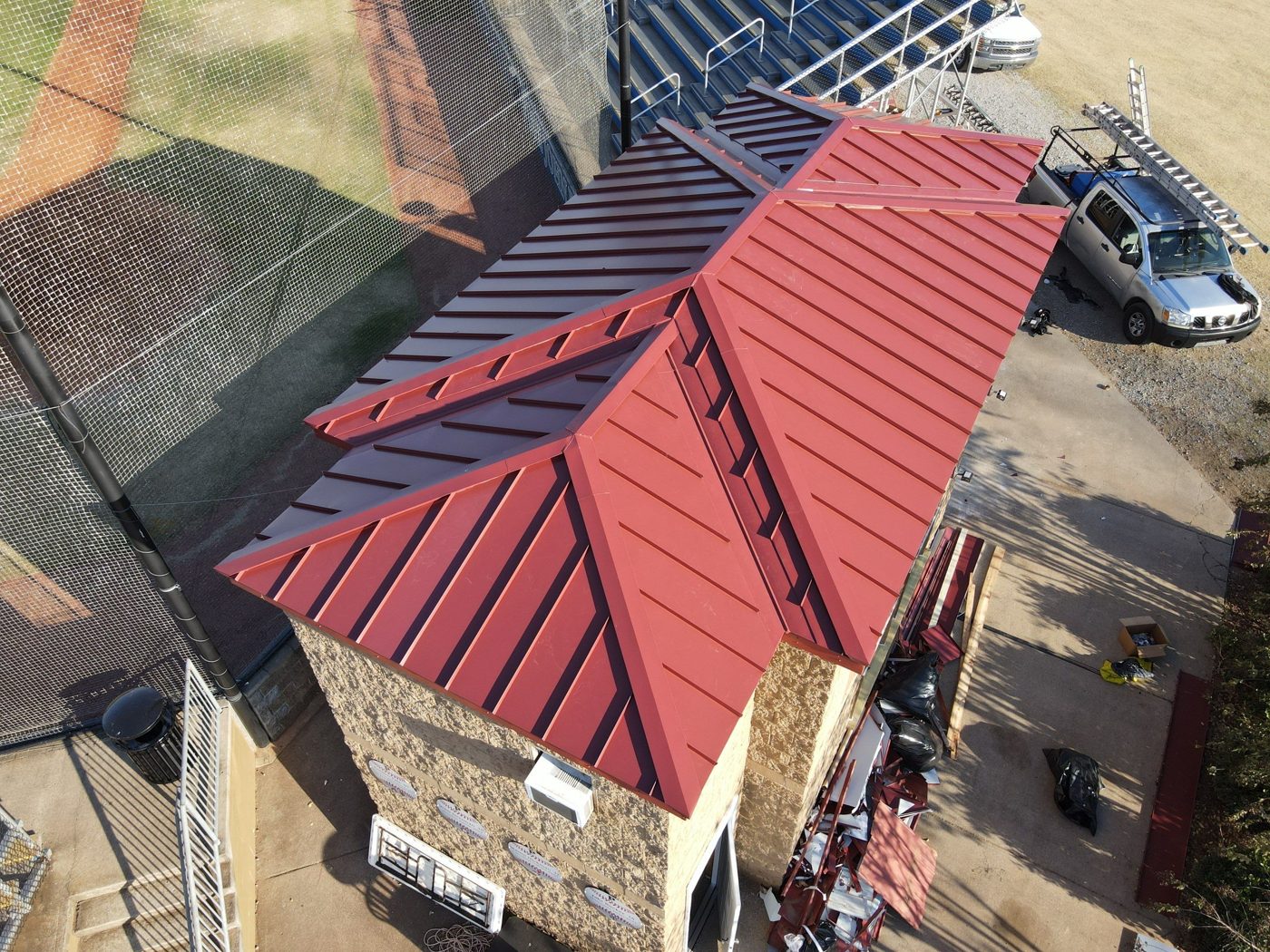 Red standing-seam metal roof on a ballfield building
